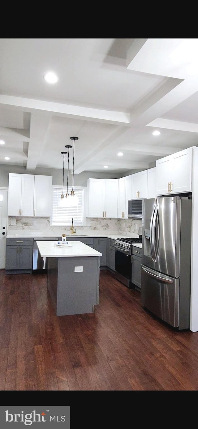 kitchen featuring appliances with stainless steel finishes, beam ceiling, dark wood finished floors, and backsplash