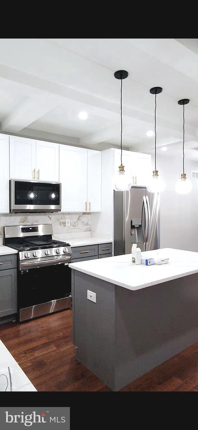 kitchen featuring appliances with stainless steel finishes, decorative backsplash, dark wood-type flooring, and pendant lighting