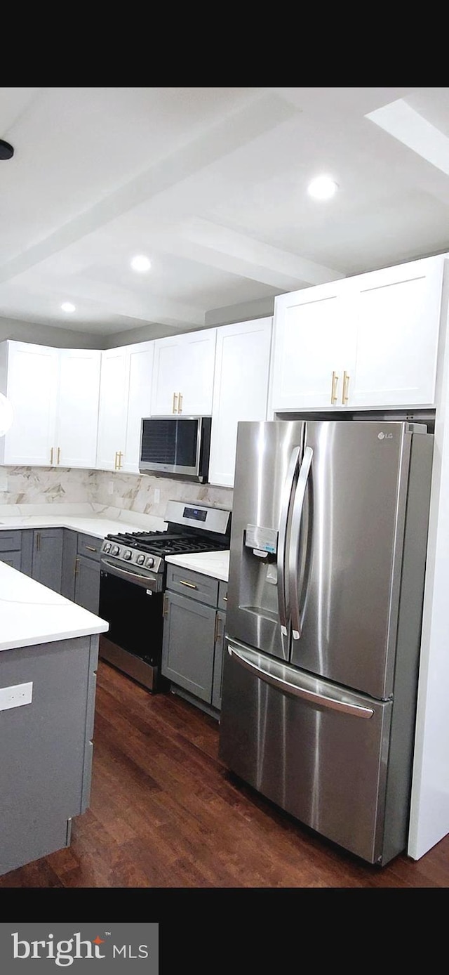 kitchen with appliances with stainless steel finishes, white cabinets, light countertops, and dark wood finished floors