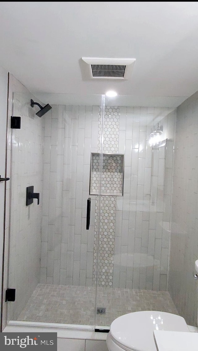 bathroom with toilet, a shower stall, and visible vents