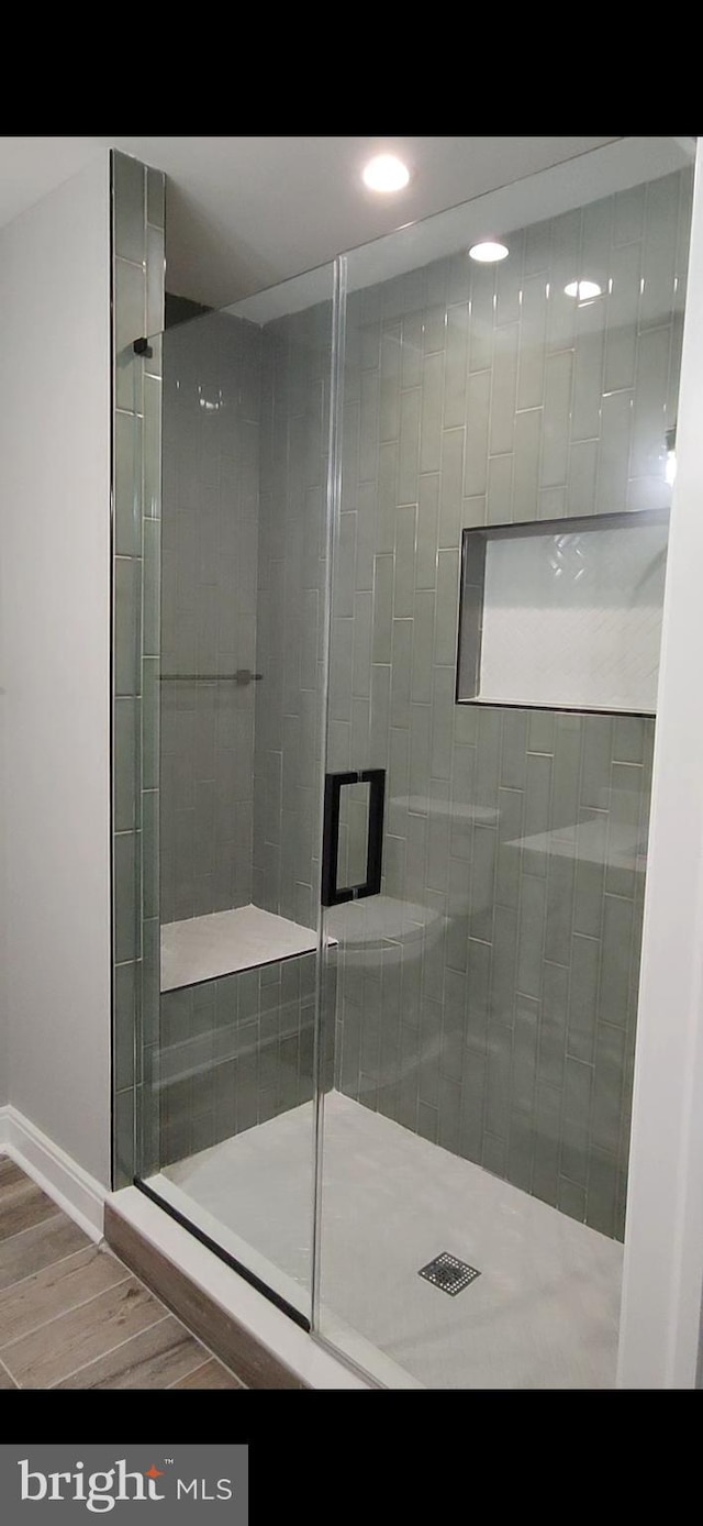 bathroom with a stall shower, wood finished floors, and baseboards