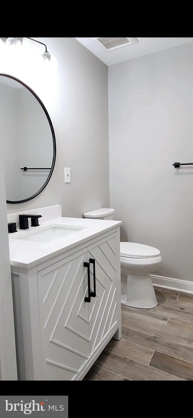 bathroom with toilet, baseboards, wood finished floors, and vanity