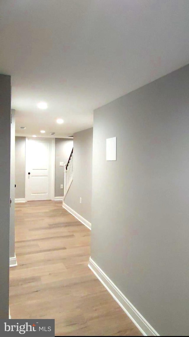 corridor featuring light wood finished floors, baseboards, stairway, and recessed lighting