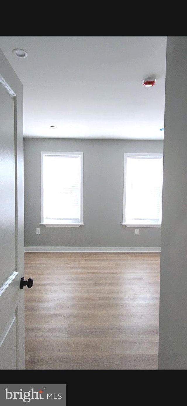 spare room with baseboards and wood finished floors