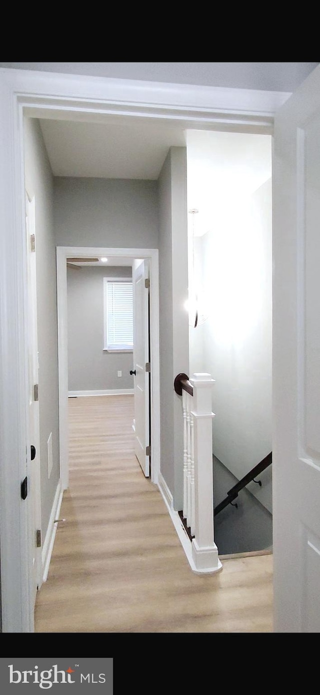 hallway with wood finished floors and an upstairs landing