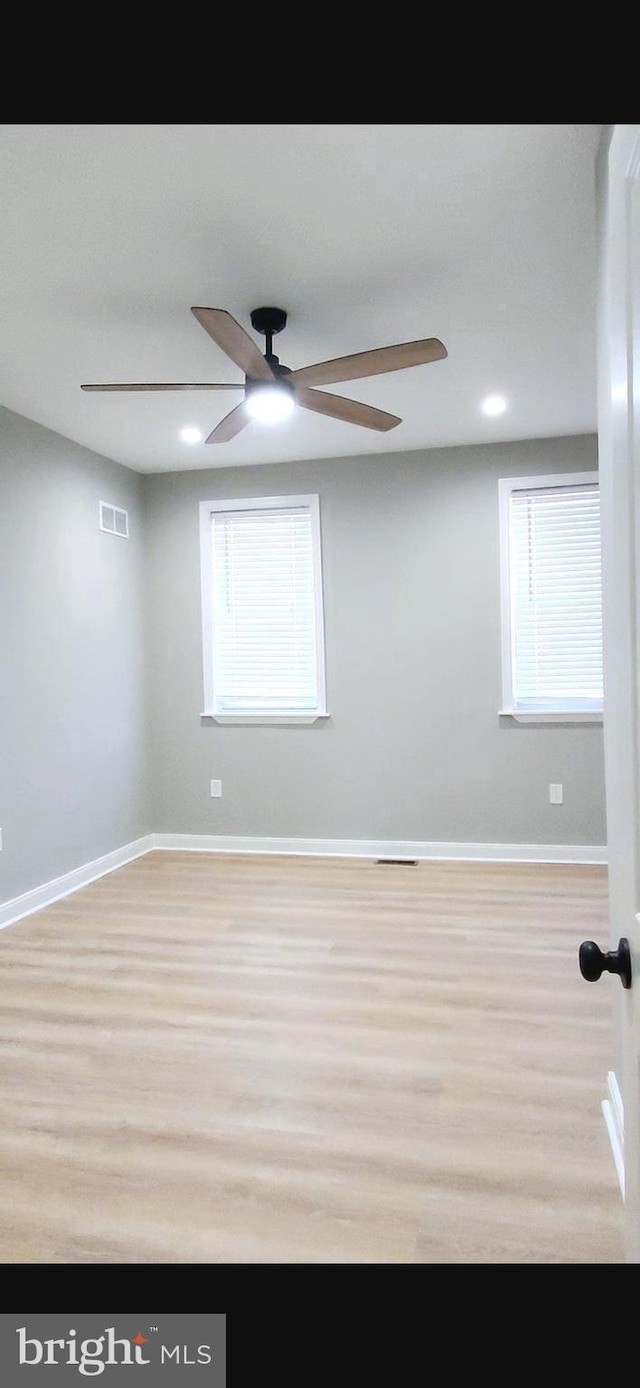 spare room with a ceiling fan, baseboards, visible vents, and wood finished floors