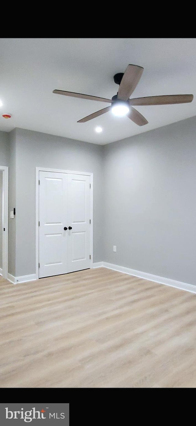 spare room featuring light wood-type flooring, ceiling fan, and baseboards