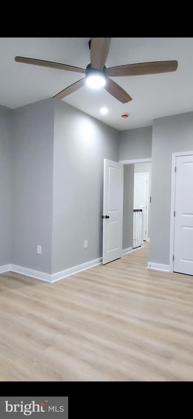 empty room with baseboards, ceiling fan, and light wood finished floors