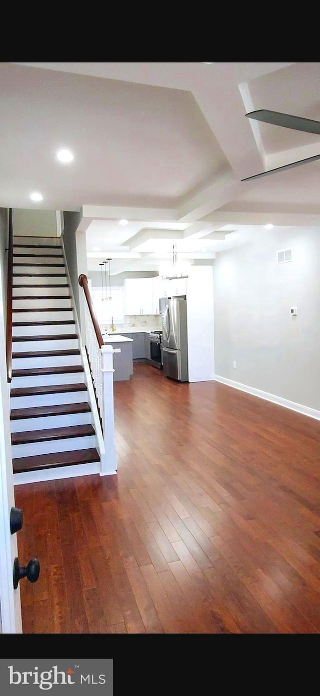 unfurnished living room featuring dark wood-style floors, visible vents, stairway, and baseboards