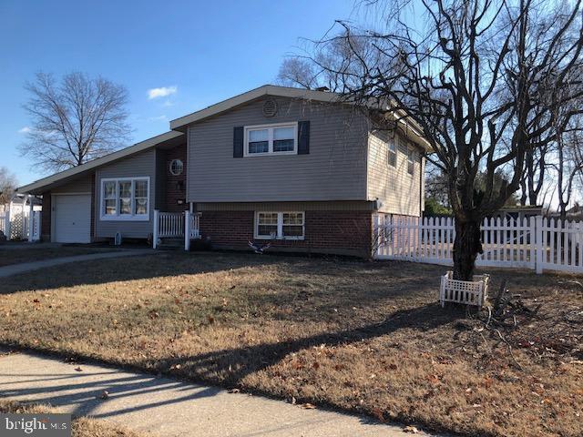 tri-level home with a garage, brick siding, and fence