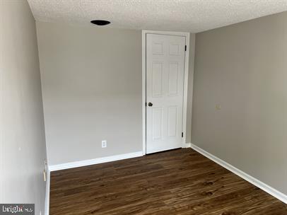 unfurnished room with dark hardwood / wood-style floors and a textured ceiling