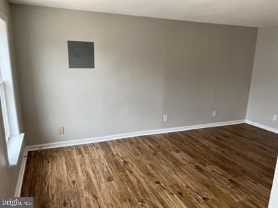 spare room featuring a textured ceiling, dark hardwood / wood-style flooring, and electric panel