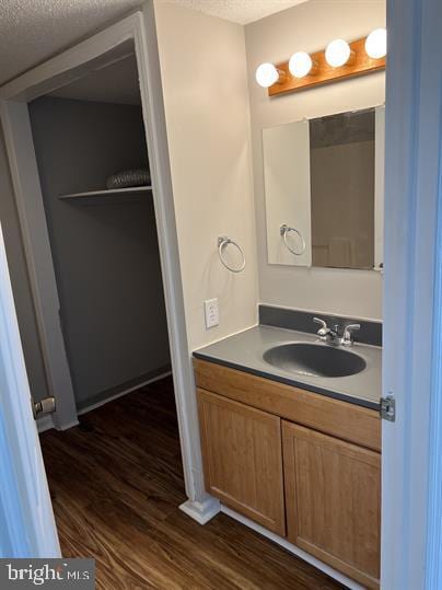 bathroom with hardwood / wood-style floors, vanity, and a textured ceiling