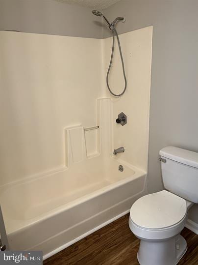 bathroom featuring hardwood / wood-style floors, a textured ceiling, toilet, and tub / shower combination