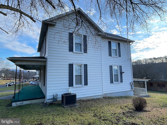 back of property featuring central air condition unit and a yard