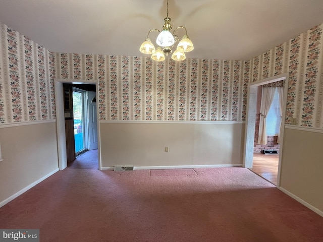 spare room featuring carpet floors and a chandelier