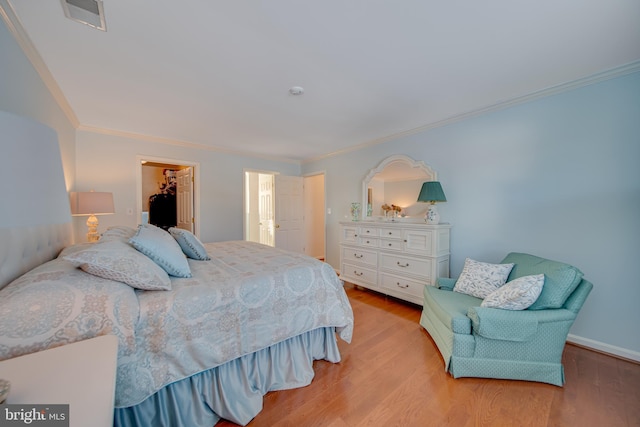 bedroom with ornamental molding, a spacious closet, light hardwood / wood-style flooring, and a closet