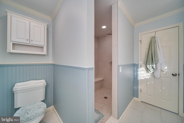 bathroom featuring tile patterned floors, crown molding, toilet, and tiled shower