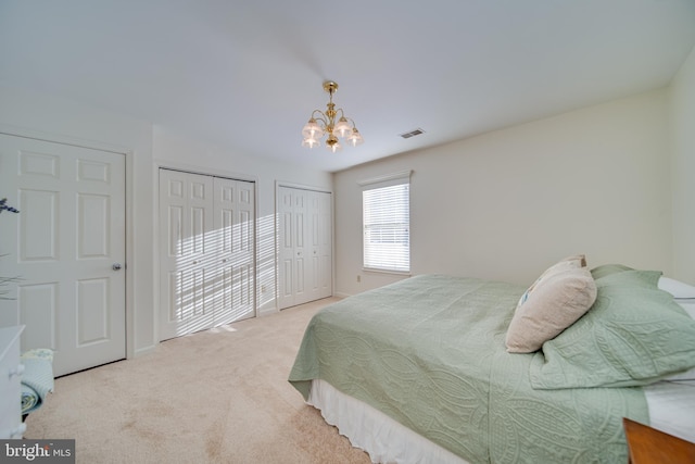 carpeted bedroom featuring a chandelier and two closets