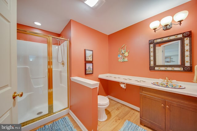 bathroom featuring hardwood / wood-style floors, vanity, toilet, and a shower with door