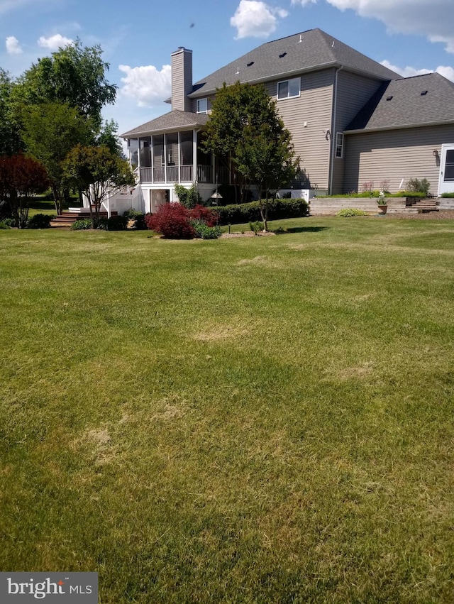 rear view of property featuring a sunroom and a yard