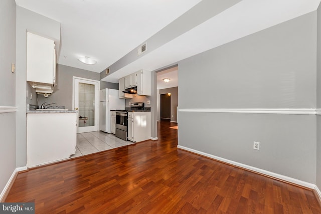 kitchen with white cabinets, light hardwood / wood-style floors, white refrigerator, and stainless steel range with electric cooktop