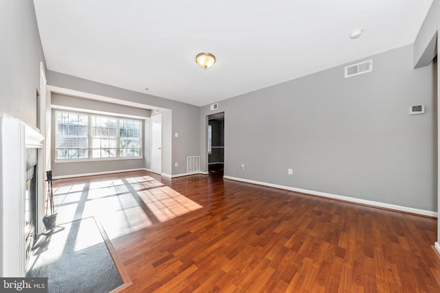 unfurnished living room featuring a high end fireplace and dark hardwood / wood-style floors