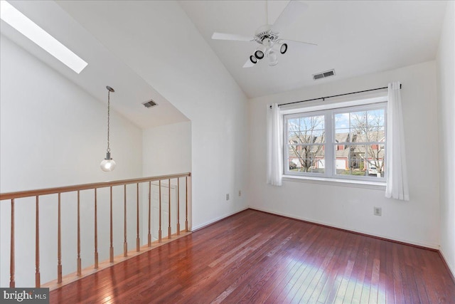 empty room featuring hardwood / wood-style floors, ceiling fan, and vaulted ceiling with skylight