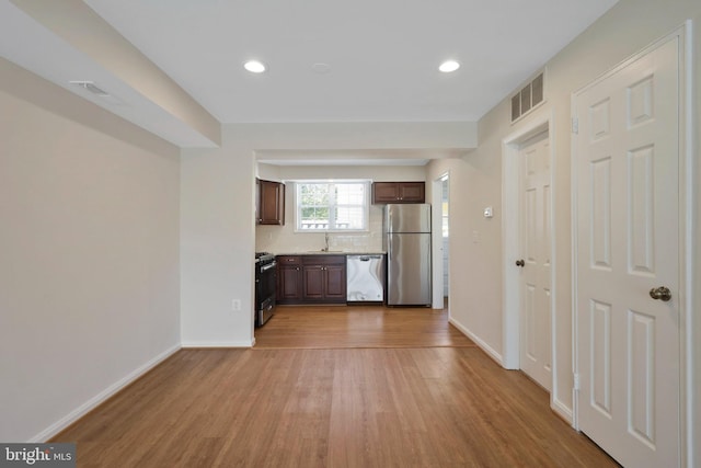 kitchen featuring sink, light hardwood / wood-style flooring, decorative backsplash, dark brown cabinetry, and stainless steel appliances