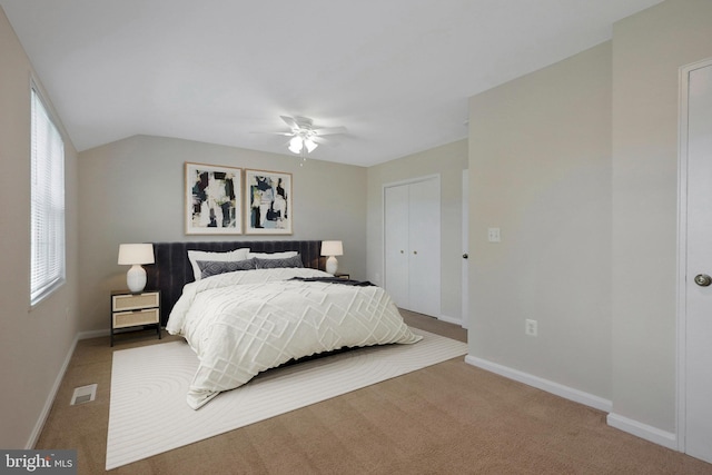 carpeted bedroom with ceiling fan, a closet, and vaulted ceiling