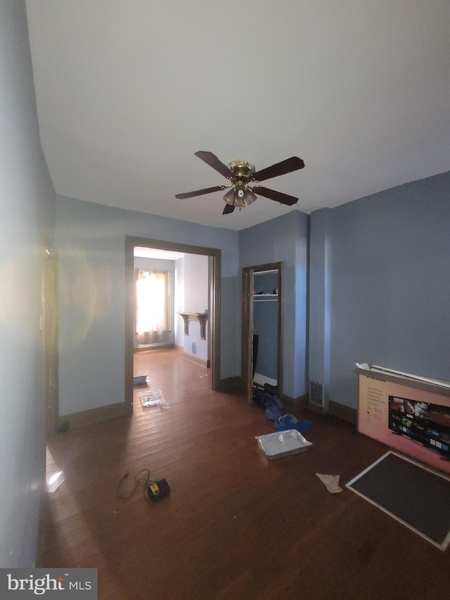 unfurnished living room featuring ceiling fan and dark hardwood / wood-style flooring