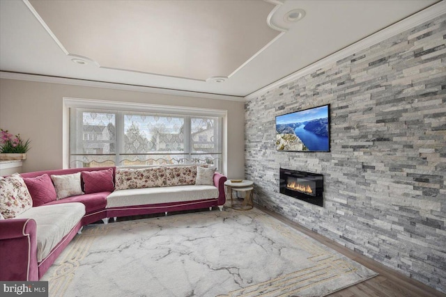 living room with a stone fireplace, wood-type flooring, and ornamental molding