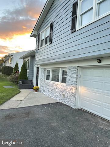 property exterior at dusk featuring a garage and a yard