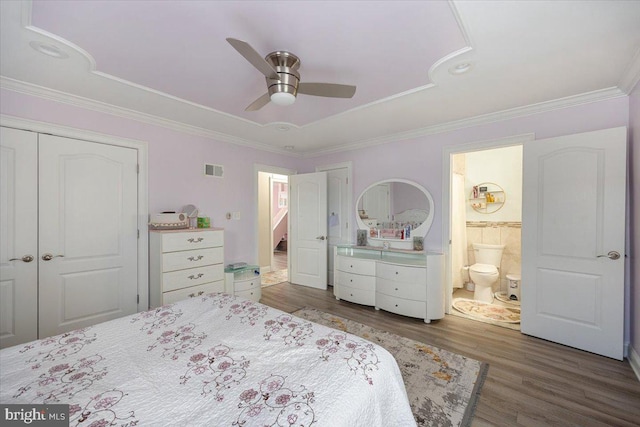 bedroom with ensuite bath, a tray ceiling, ceiling fan, dark hardwood / wood-style floors, and a closet