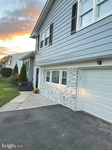 property exterior at dusk featuring a lawn and a garage