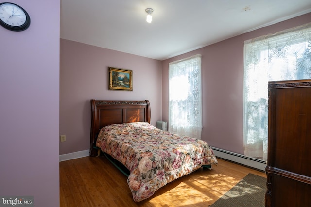 bedroom with wood finished floors, baseboards, and baseboard heating