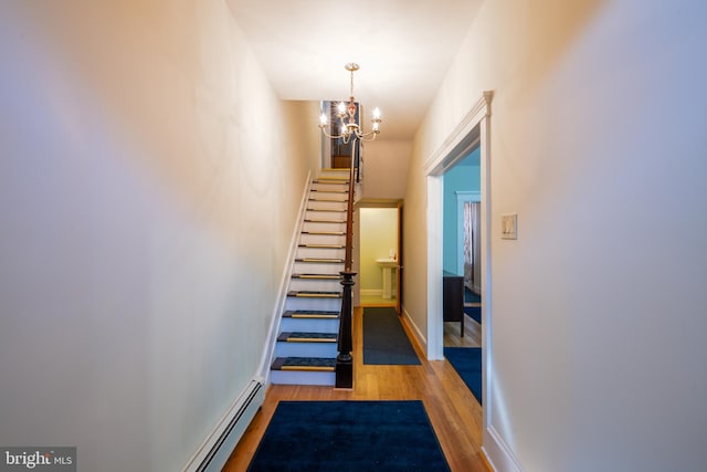 staircase with a chandelier, baseboards, and wood finished floors