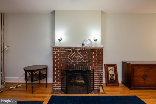 living area featuring baseboards, wood finished floors, and a fireplace