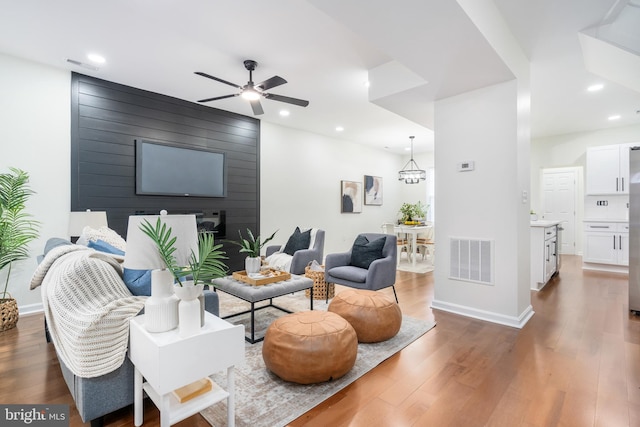 living room featuring ceiling fan with notable chandelier and dark hardwood / wood-style floors