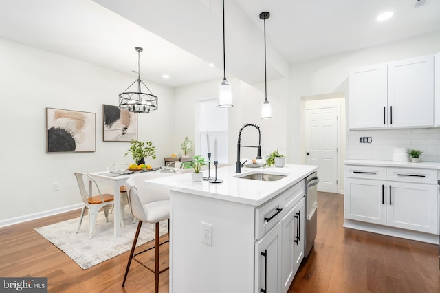 kitchen featuring white cabinetry, sink, an island with sink, and decorative light fixtures