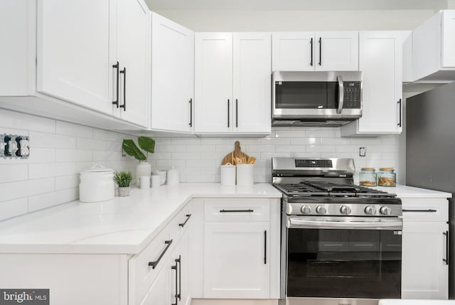 kitchen with backsplash, white cabinetry, light stone countertops, and appliances with stainless steel finishes