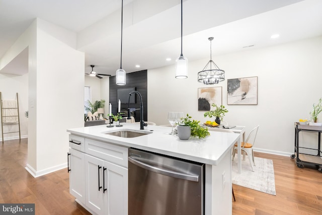 kitchen featuring sink, stainless steel dishwasher, decorative light fixtures, a center island with sink, and white cabinets