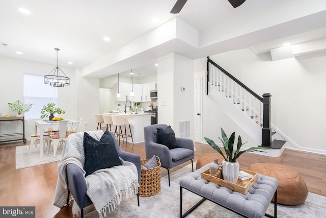 living room featuring a notable chandelier, light hardwood / wood-style floors, and sink