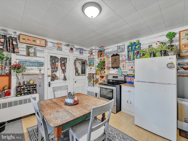 kitchen with stainless steel range with electric stovetop, ornamental molding, white cabinets, radiator heating unit, and white fridge