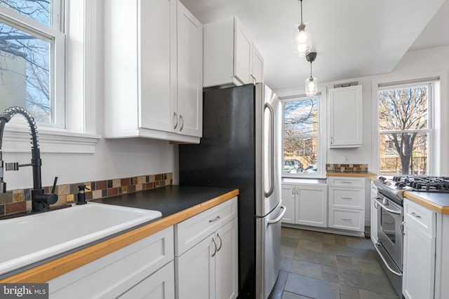 kitchen featuring hanging light fixtures, sink, white cabinets, and stainless steel appliances