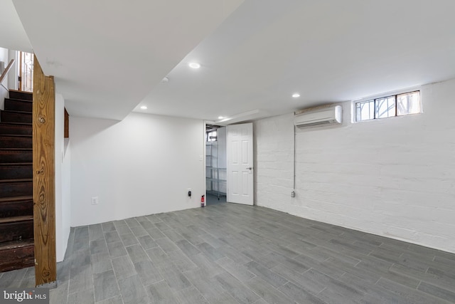 basement featuring hardwood / wood-style flooring and an AC wall unit