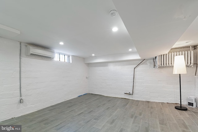 basement featuring a wall mounted air conditioner and hardwood / wood-style flooring