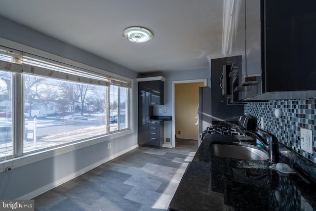 kitchen with sink, dark stone countertops, decorative backsplash, stove, and fridge