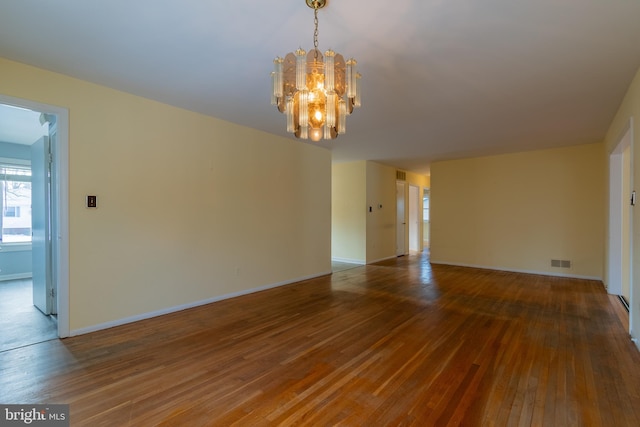 unfurnished room featuring hardwood / wood-style flooring and a chandelier