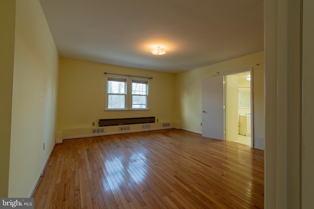 spare room with washer / dryer and light wood-type flooring